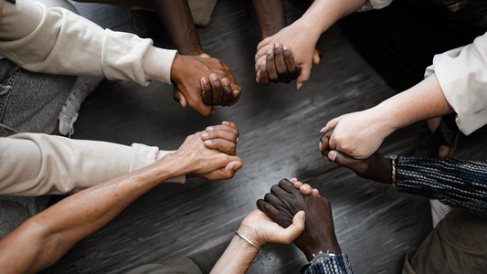 A group of smiling people holding hands in a circle, symbolizing community and gratitude.